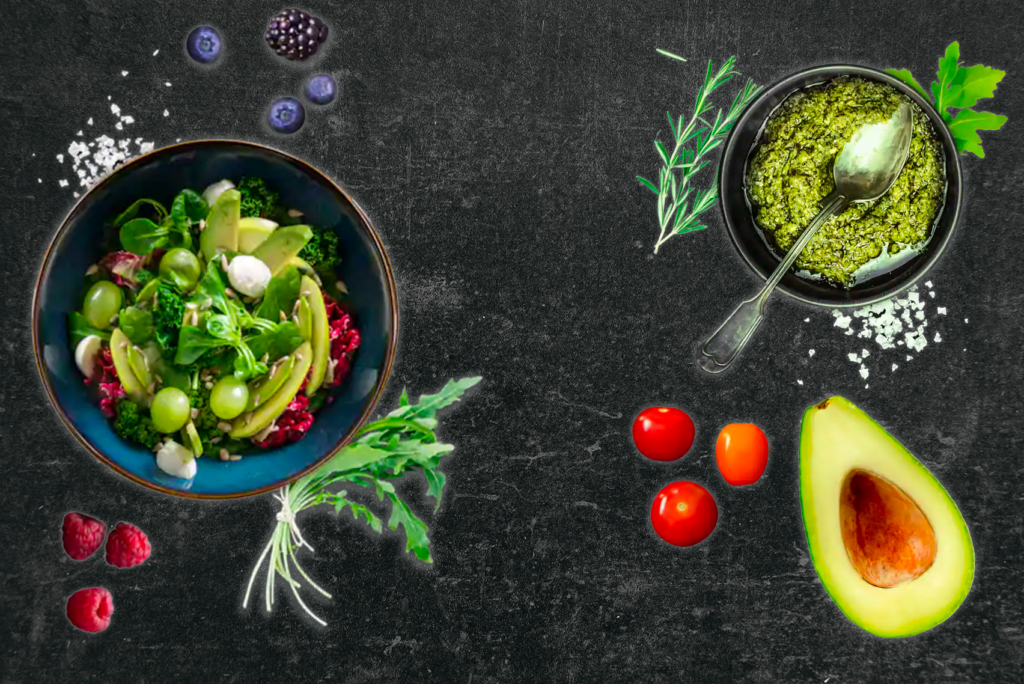 Links ist ein Salat mit Avocado, Gemüse und Trauben in einer Schüssel zu sehen. Rechts ist eine Schüssel mit grünem Pesto, einer Avocadohälfte, Kirschtomaten, Rosmarin und Petersilie auf einem dunklen strukturierten Hintergrund. Überall sind Beeren und Kräuter verstreut.