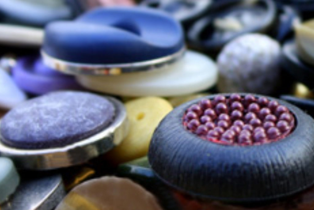 Eine Nahaufnahme verschiedener bunter Knöpfe mit unterschiedlichen Texturen, Größen und Designs. Einige Knöpfe haben glatte Oberflächen, während andere einzigartige Muster aufweisen, darunter ein Knopf mit roten, perlenartigen Details.