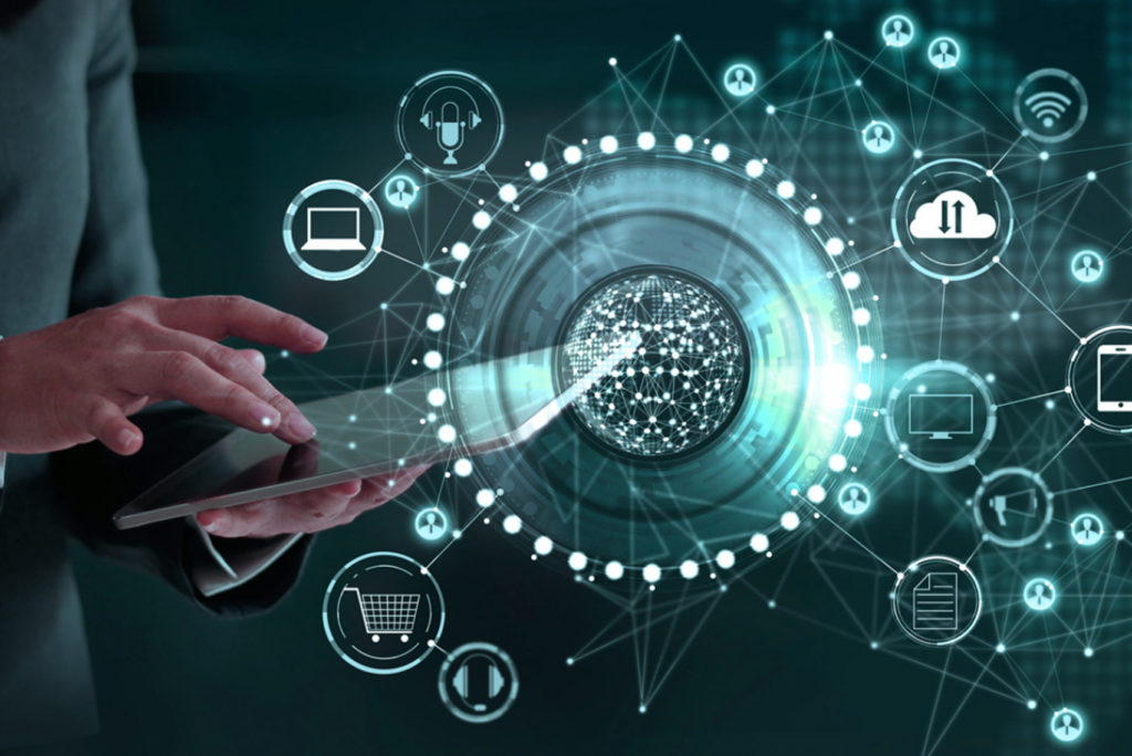 Eine Person, die ein Tablet mit verschiedenen digitalen Symbolen wie einem Einkaufswagen, einem Laptop und einem Telefon verwendet, die einen Globus umgeben. Das Bild suggeriert globale Konnektivität und digitale Kommunikation. Der Hintergrund ist dunkel mit leuchtend weißen Linien und Knoten.