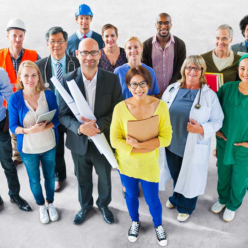 Eine bunt gemischte Gruppe von Fachleuten, darunter Ärzte, Ingenieure und Büroangestellte, steht lächelnd zusammen. Sie tragen unterschiedliche Arbeitskleidung – Laborkittel, OP-Kleidung, Anzüge und Baukleidung – und verkörpern damit den Beginn einer gemeinsamen Reise über verschiedene Berufe hinweg.