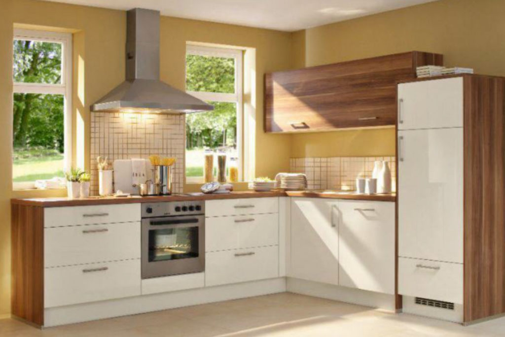 Moderne Küche mit weißen Schränken und Holzarbeitsplatten. Ein Ofen mit Kochfeld steht mittig unter einer Dunstabzugshaube aus Edelstahl. Natürliches Licht fällt durch zwei Fenster ein. Die Oberschränke sind aus Holz und auf der Arbeitsplatte stehen Topfpflanzen.