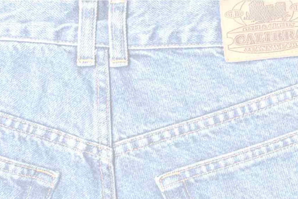 Nahaufnahme der Rückseite einer hellblauen Jeans mit Gürtelschlaufen, einem Lederpatch mit Ziernähten und sichtbaren Nähten. Die Stoffstruktur und das traditionelle Jeansdesign sind deutlich zu erkennen.