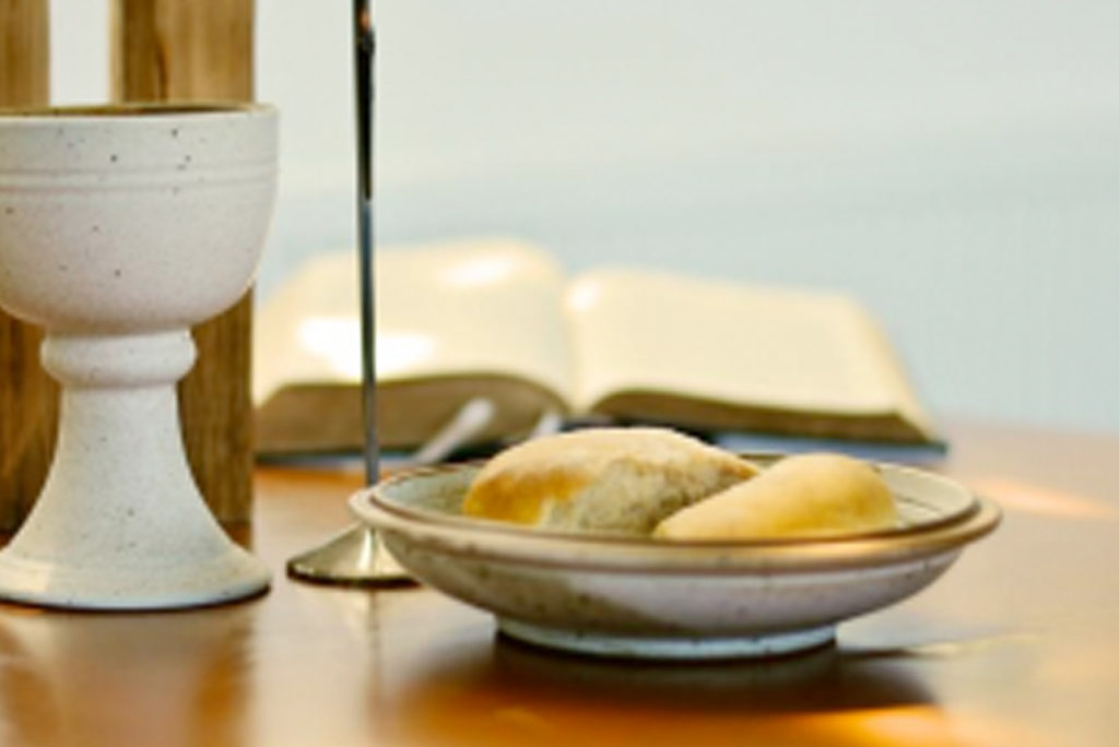 Ein Tisch mit einem Teller mit zwei Brötchen, einer Keramiktasse und einem offenen Buch im Hintergrund, sanft beleuchtet, was eine heitere und besinnliche Atmosphäre suggeriert.