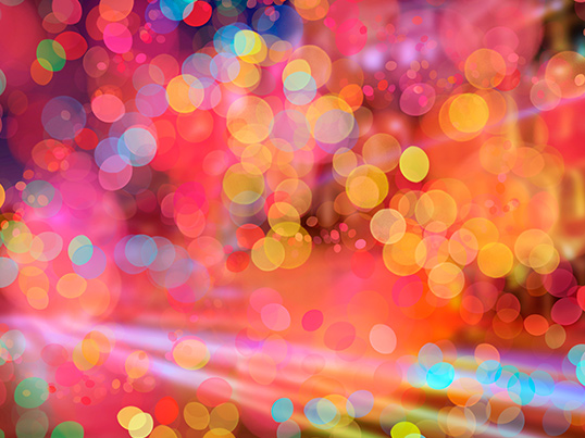 Ein lebendiger, farbenfroher Bokeh-Hintergrund mit überlappenden Lichtkreisen in verschiedenen Größen und Farben, darunter Rot, Orange, Gelb, Blau und Pink, die einen festlichen und abstrakten visuellen Effekt erzeugen.