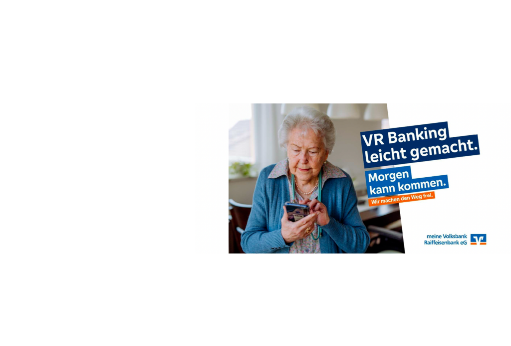 Eine ältere Frau schaut in einem Wohnzimmer auf ihr Smartphone. Der Text auf dem Bild lautet auf Deutsch: "VR Banking leicht gemacht. Morgen kann kommen. Wir machen den Weg frei." Das Logo von "meine Volksbank Raiffeisenbank eG" ist zu sehen.