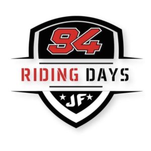 Logo in Schildform mit der Nummer „94“ in fetter roter Schrift oben. Darunter wird der Text „Riding Days“ in Rot und Schwarz angezeigt und unten sind die Initialen „JF“ mit zwei Sternen zu sehen.